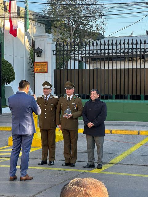 Entrega de un reconocimiento a dos carabineros frente a la reja del cuartel