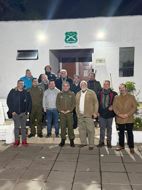 Foto de grupo de noche frente a un cuartel con el escudo de Carabineros