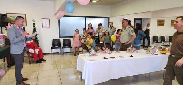 Familias y carabineros reunidos en el salón decorado con globos