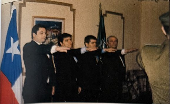 Cuatro nuevos alguaciles prestan juramento con el brazo extendido, junto a la bandera de Chile (2004)